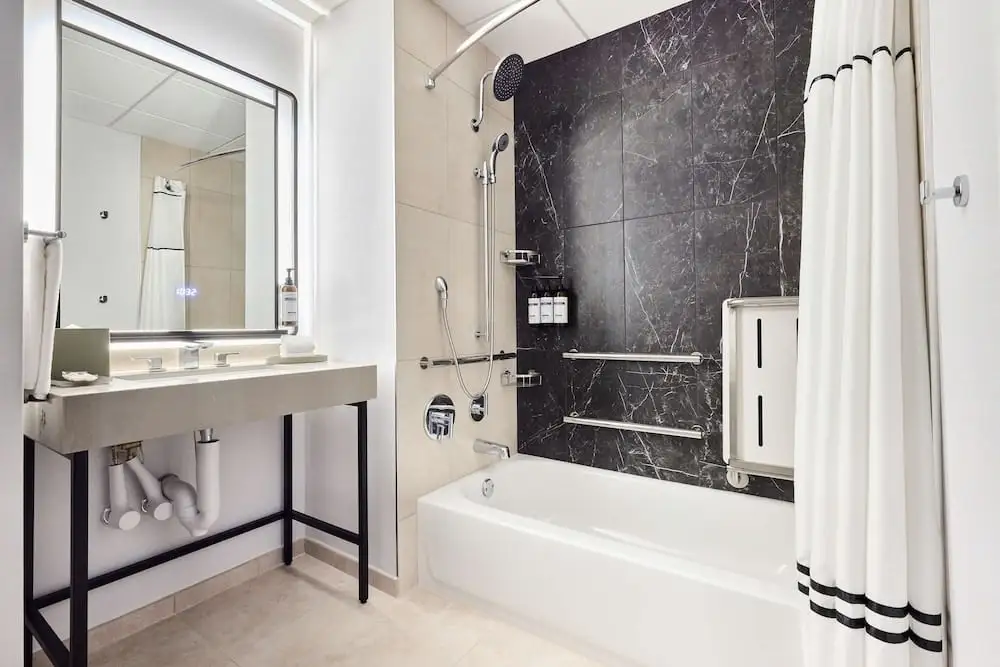 Renovated bathroom at Hyatt Regency Chicago after the 2024 renovation - black marble tiles in the shower area, white bathtub, modern sink on a metal frame