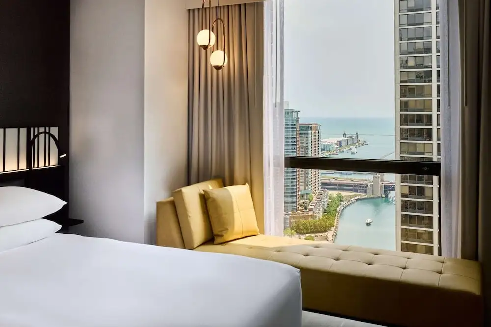 A Hyatt Regency Chicago room with panoramic views of Lake Michigan and Navy Pier - a double bed, yellow sofa by a floor-to-ceiling window